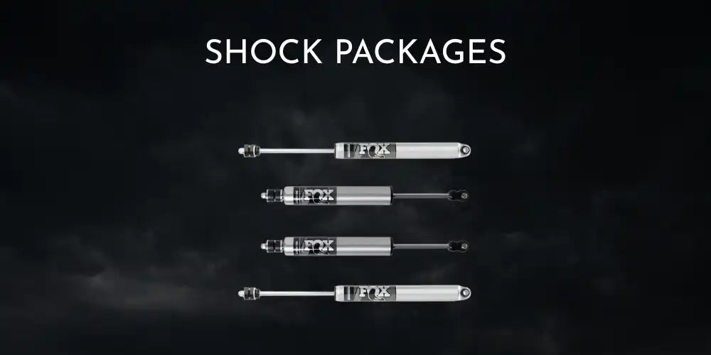 Four light-colored vehicle shock absorbers with black accents.