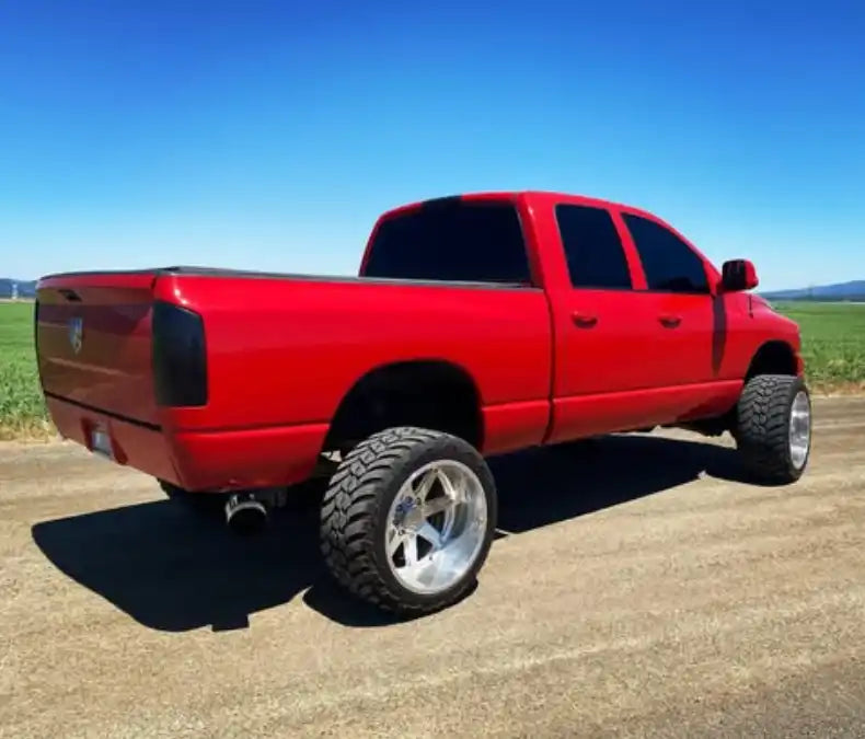 Red lifted pickup truck with large chrome wheels and tinted windows.