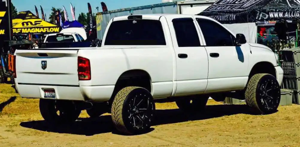 White four-door pickup truck with black aftermarket wheels.